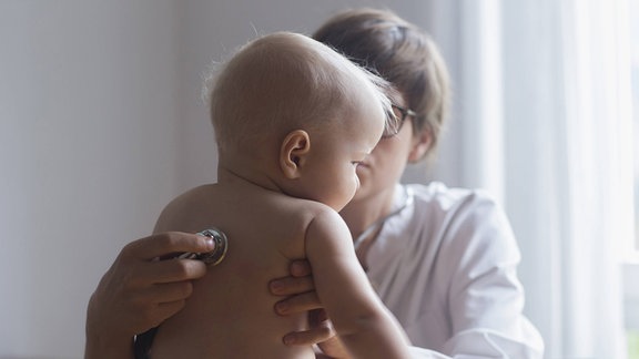 Eine Kinderärztin untersucht einen kleinen Jungen in einer Klinik. Bei den regelmäßigen Früherkennungsuntersuchungen (U1-U9) sprechen Ärzte mit den Eltern auch über empfohlene und anstehende Impfungen.