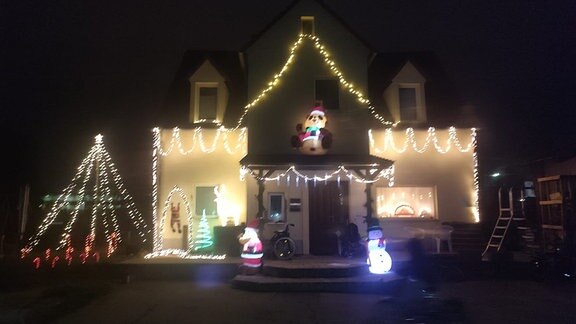 Weihnachtlich geschmücktes Haus von außen mit vielen bunten Lichterketten.