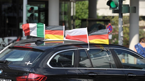 Fahrzeug mit den Flaggen von Deutschland, Polen und Italien an einem Auto