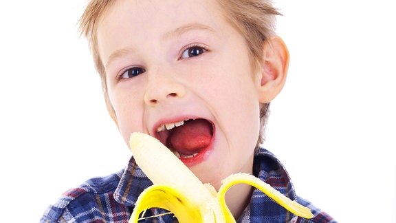 Ein Junge hält eine geschälte Banane in der Hand