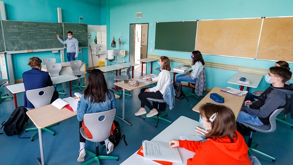 Schulalltag in der Corona-Pandemie: Schüler eines Gymnasiums sitzen mit Mundschutz und mit viel Abstand im Klassenraum