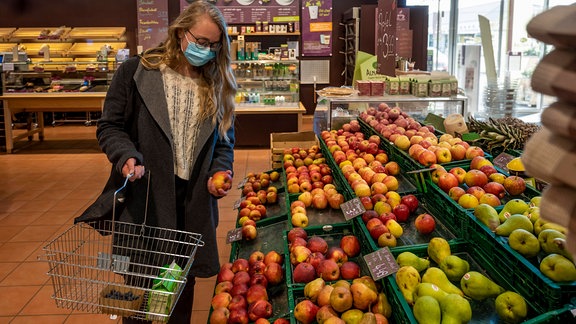 Eine Frau mit Mundschutz in der Obst- und Gemüseabteilung