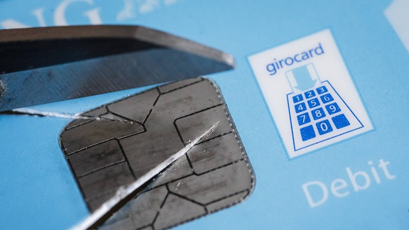 Der Chip einer Girocard wird mit einer Schere zerschnitten