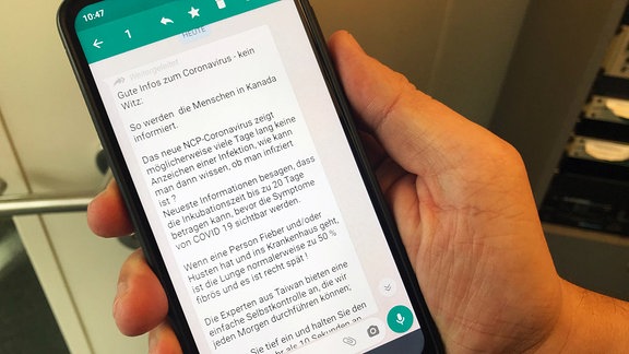 Smartphone mit Kettenbrief auf WhatsApp mit vermeintlichen Tipps zum Schutz vor dem Coronavirus