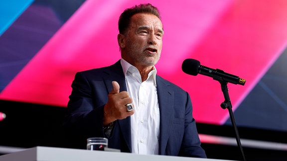 Arnold Schwarzenegger an einem Podium beim Reden