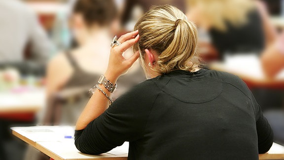Schüler sitzen mit dem Rücken zum Betrachter in einer Prüfung