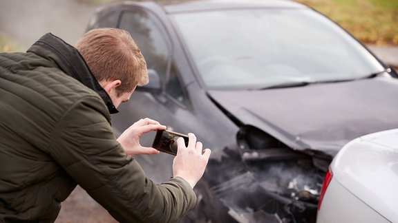 Autofahrer nimmt einen Unfall für die Versicherung auf (Symbolfoto)