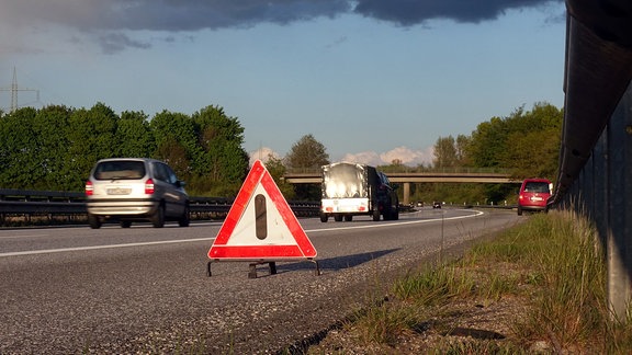 Auf dem Standstreifen der A24 weist ein Warndreieck Autofahrer auf ein Fahrzeug mit einer Panne hin.
