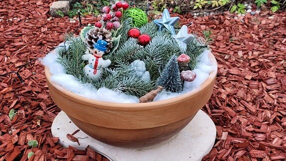 Weihnachtsdekoration im Garten. Ein Topf voller Tanne und weihnachtlichen Utensilien.